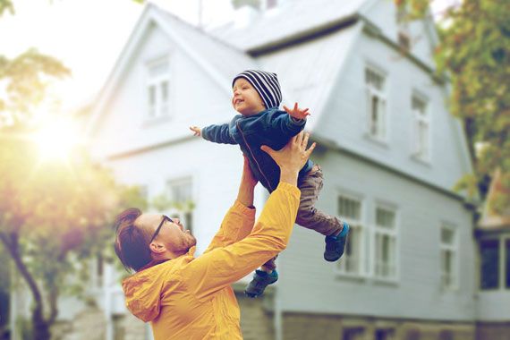 Un papa qui tient son fils au bout de ses bras.