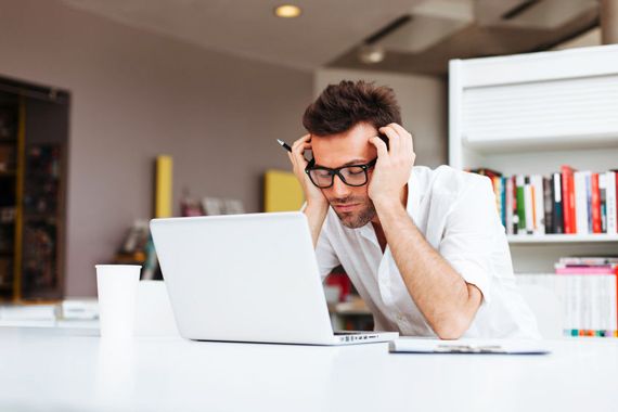 Un homme se tient la tête devant son ordinateur.